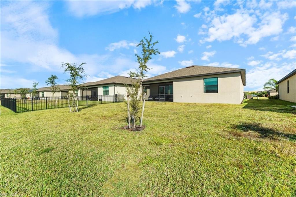 Expansive grassy yard with young trees and a partial privacy fence
