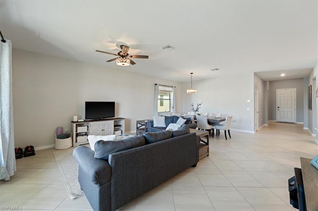Open-concept living space featuring light-toned tile flooring, a contemporary ceiling fan, and recessed lighting