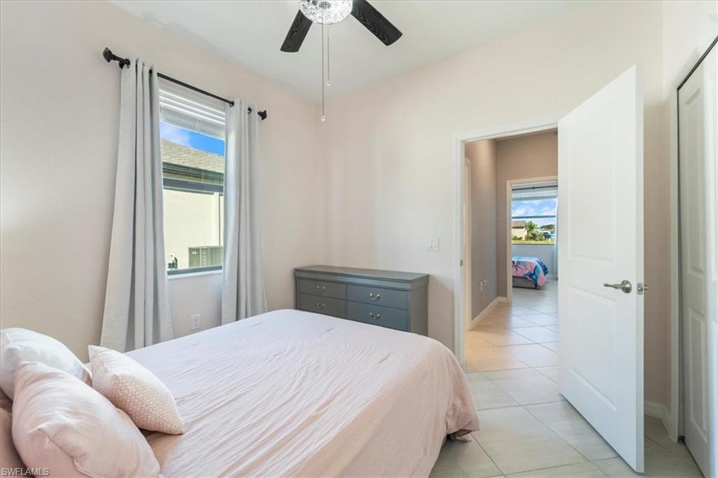 Bedroom featuring a window with blinds and drapes, a ceiling fan with light fixture, and tile flooring
