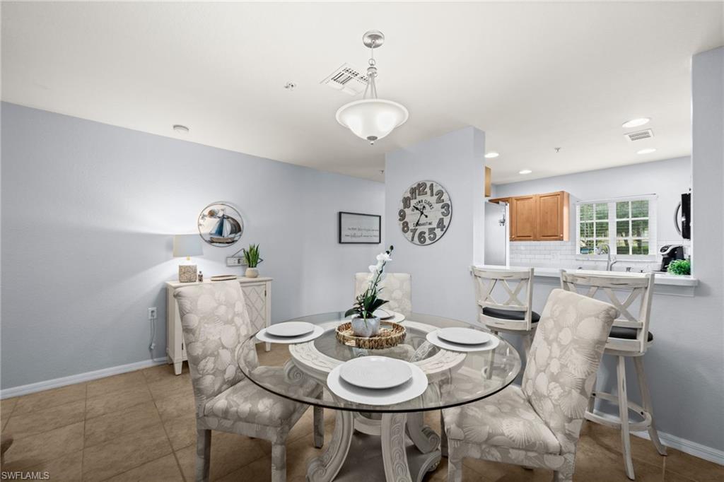 Bright dining area featuring tile flooring, a glass-top table, and a contemporary pendant light fixture
