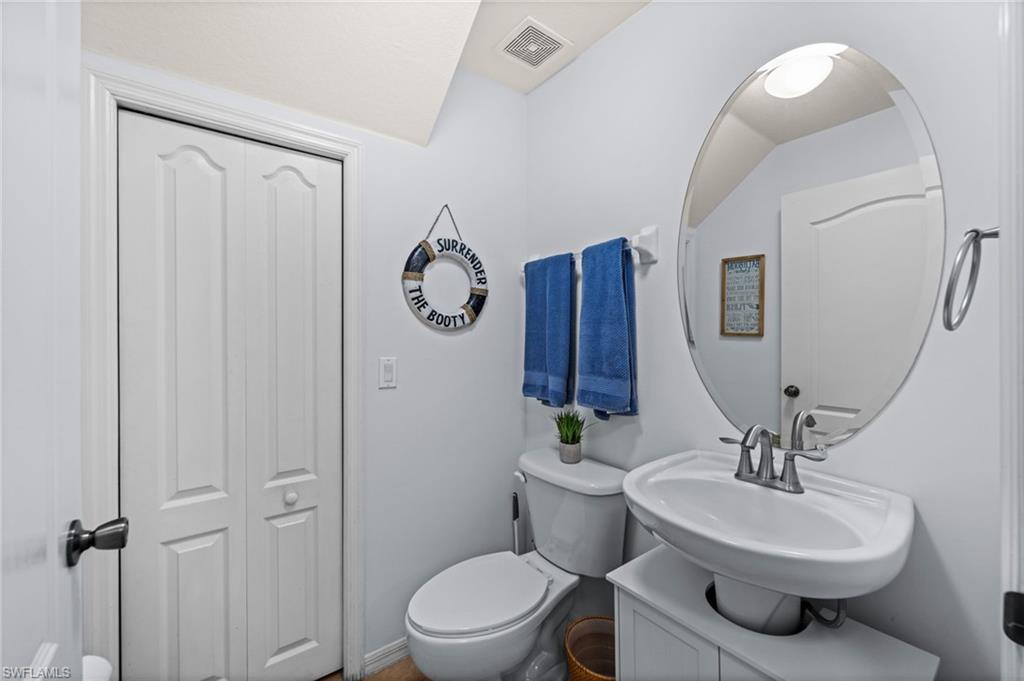 Powder room with a white pedestal sink, dual-handle faucet, and an oval mirror