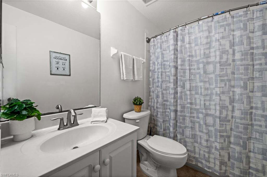 Bathroom featuring a vanity with an integrated sink, brushed nickel faucet, full-width mirror, and a toilet