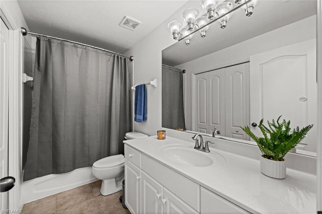 Full bathroom featuring a single vanity with a white countertop and integrated sink, brushed nickel faucet, large wall mirror, and overhead vanity lighting