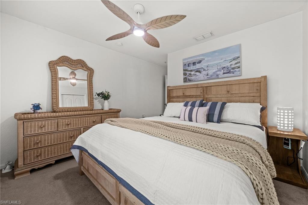 Bedroom featuring wood-finish flooring, a ceiling fan with integrated lighting, and a rustic wood headboard