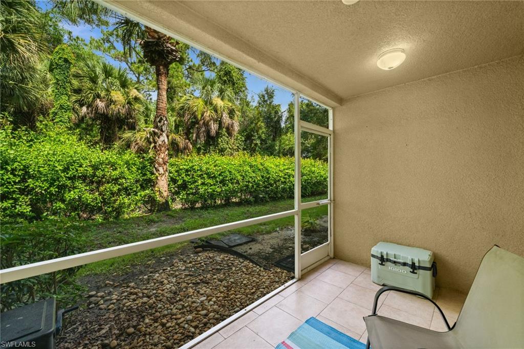 Screened lanai featuring tile flooring, textured wall finish, and a ceiling-mounted light fixture