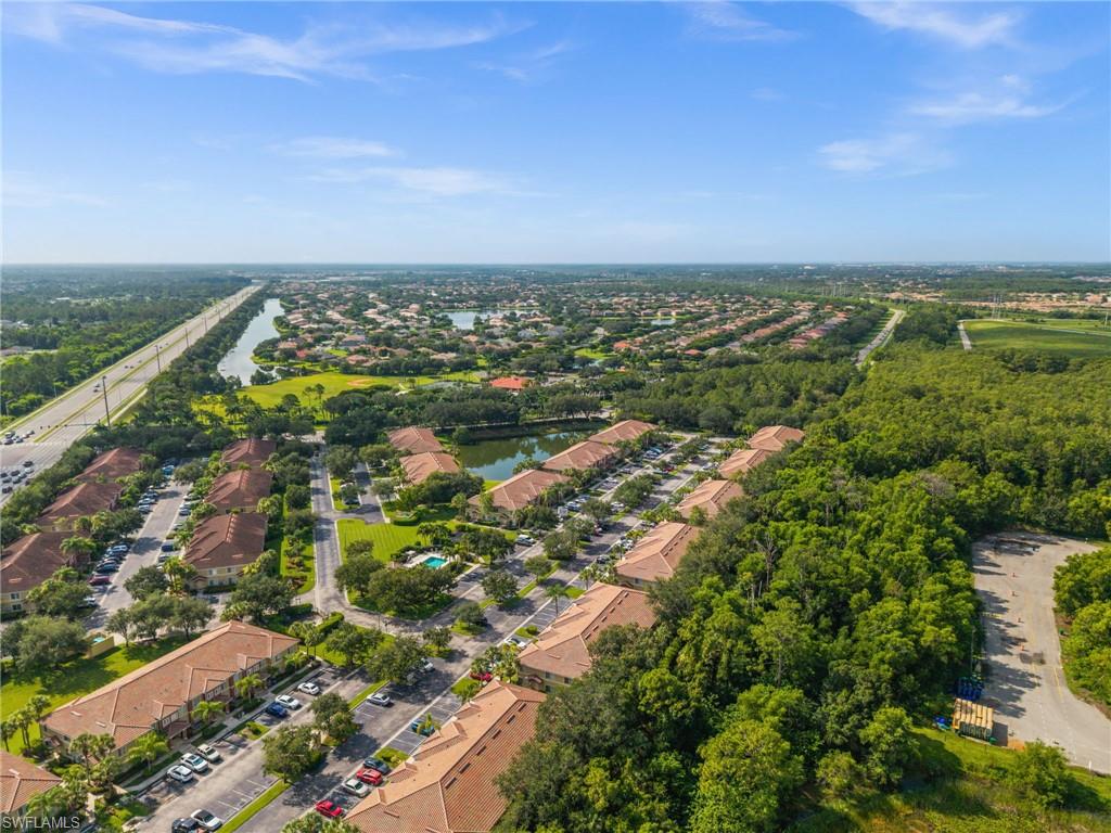 Aerial perspective showcasing a community with terracotta-roofed buildings, a central body of water, and extensive green spaces