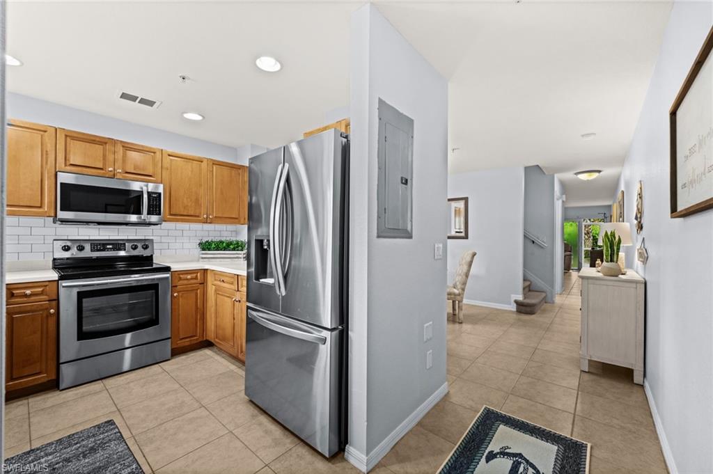 Gourmet kitchen with stainless steel appliance suite, light wood cabinetry, white subway tile backsplash, and light countertops