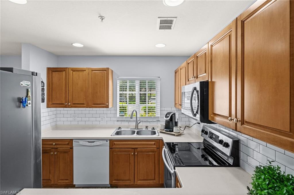 Kitchen featuring light wood cabinetry, white subway tile backsplash, white countertops, and recessed lighting