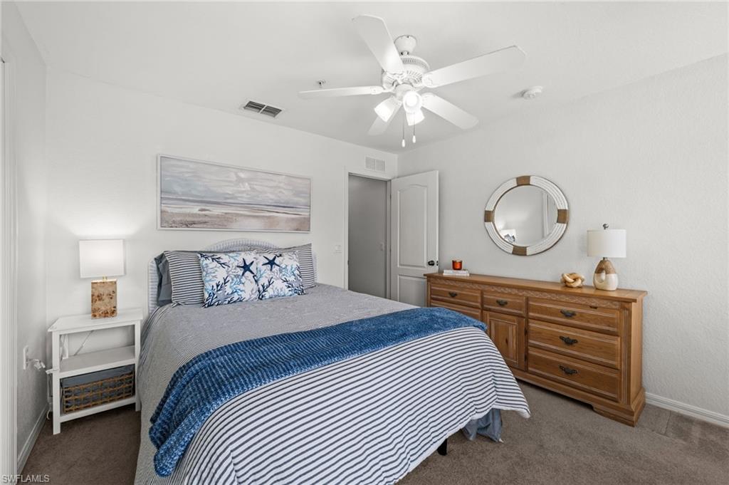 Bedroom featuring a ceiling fan with integrated lighting, textured wall finishes, and carpet flooring