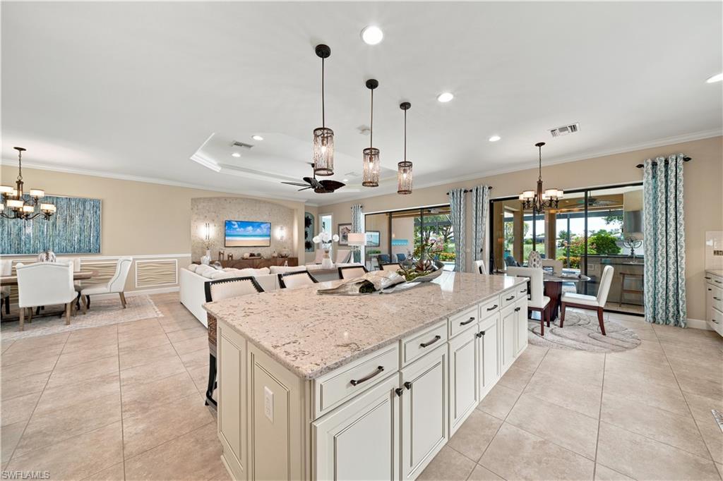 Spacious open-concept interior featuring a large kitchen island with a light-colored countertop, recessed lighting, and tile flooring