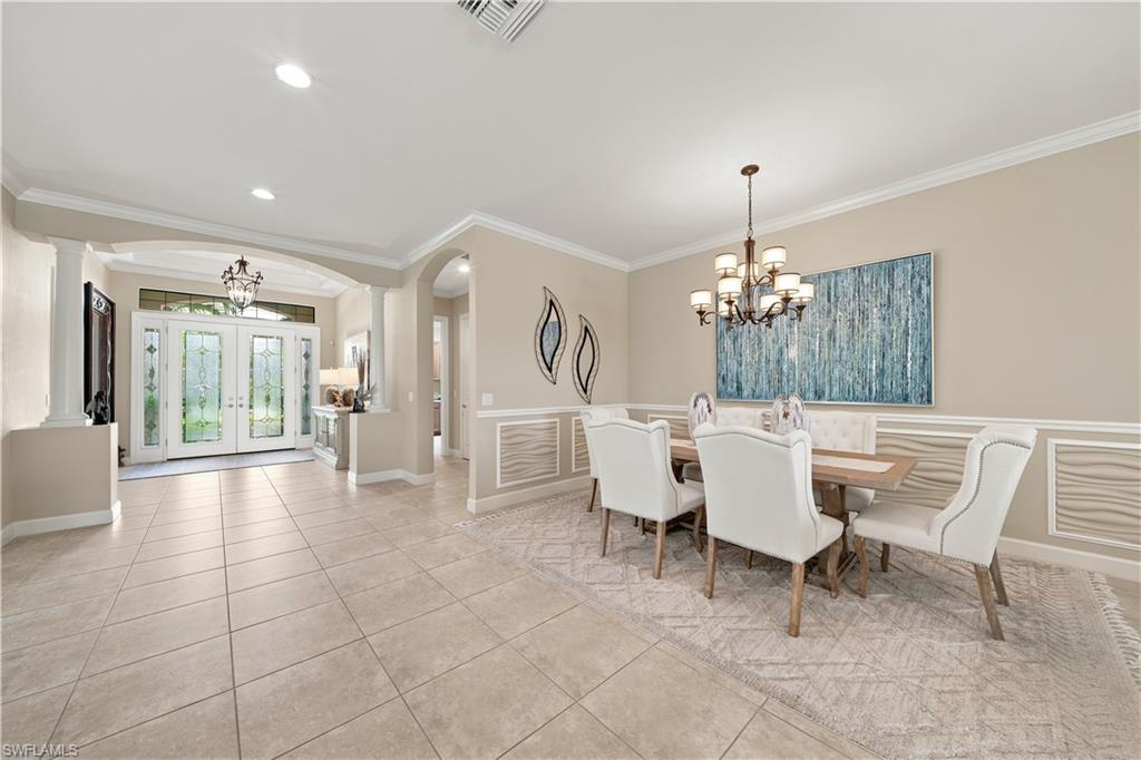 Formal dining area featuring wainscoting and crown molding, tile flooring, and a chandelier