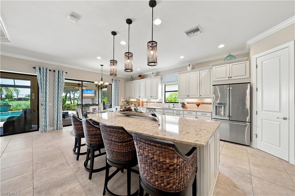 Spacious kitchen featuring a large island with a light-toned countertop, white cabinetry, stainless steel appliances, and tile flooring