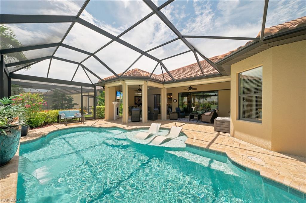 Screened lanai featuring a swimming pool with integrated sun shelf and brick paver decking