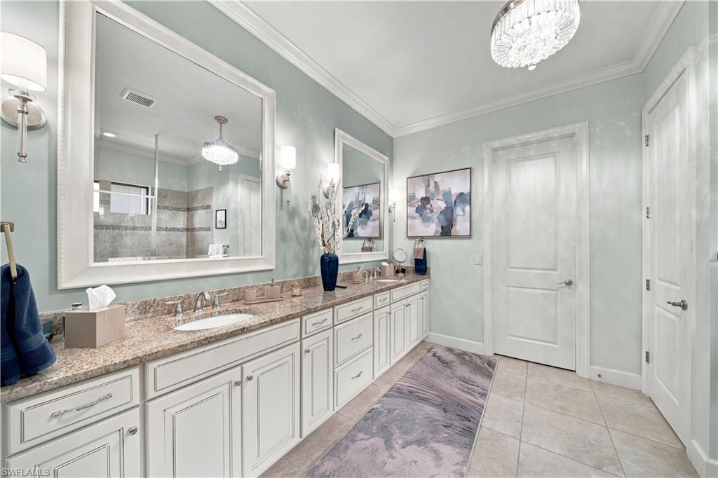 Spacious bathroom featuring a dual vanity with light-toned granite-style countertops, white cabinetry, and undermount sinks