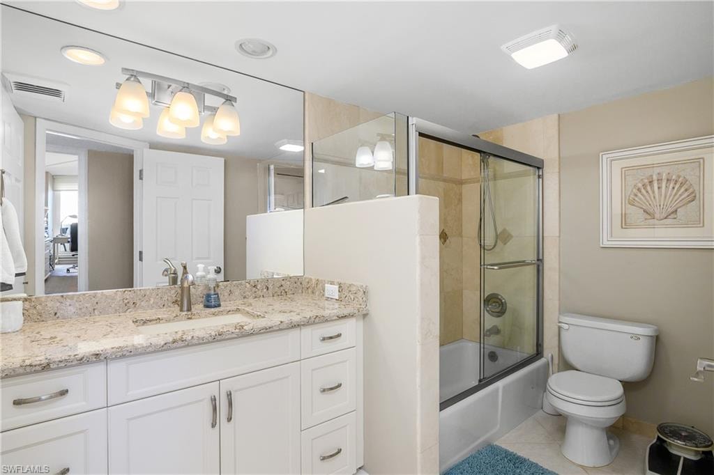 Full bathroom featuring vanity, tile patterned flooring, enclosed tub / shower combo, and toilet