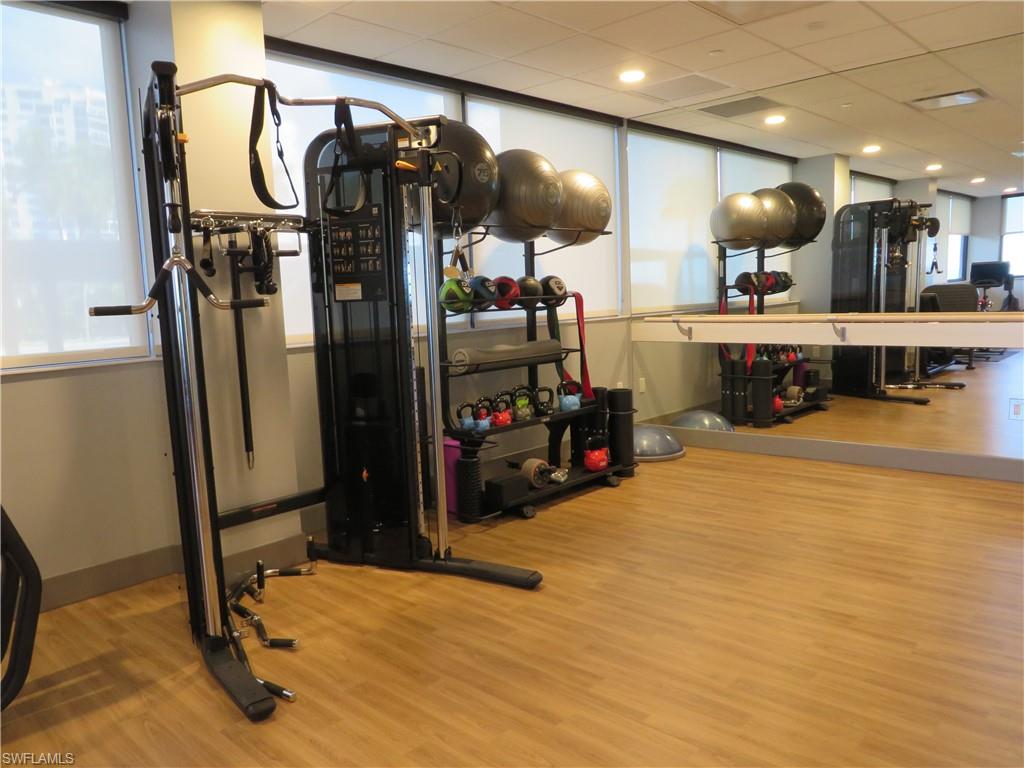 Exercise room with light wood-style floors and a drop ceiling