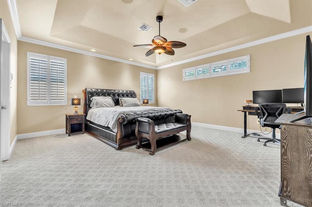 Spacious room featuring a tray ceiling, ceiling fan, recessed lighting, and patterned carpet flooring