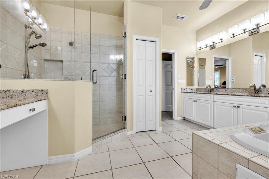 Bathroom featuring an enclosed glass shower, dual vanity with granite countertop, built-in bathtub, and ceramic tile flooring