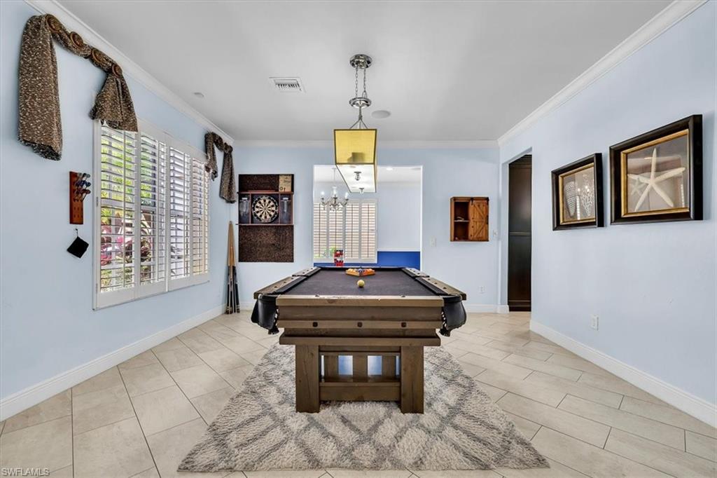 Spacious room featuring light blue walls, crown molding, and large window with white plantation shutters