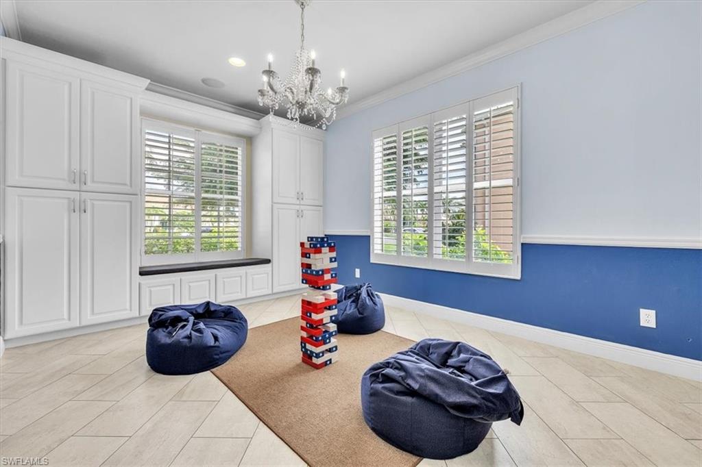 Room featuring built-in white cabinetry, window seating, plantation shutters, and a chandelier lighting fixture