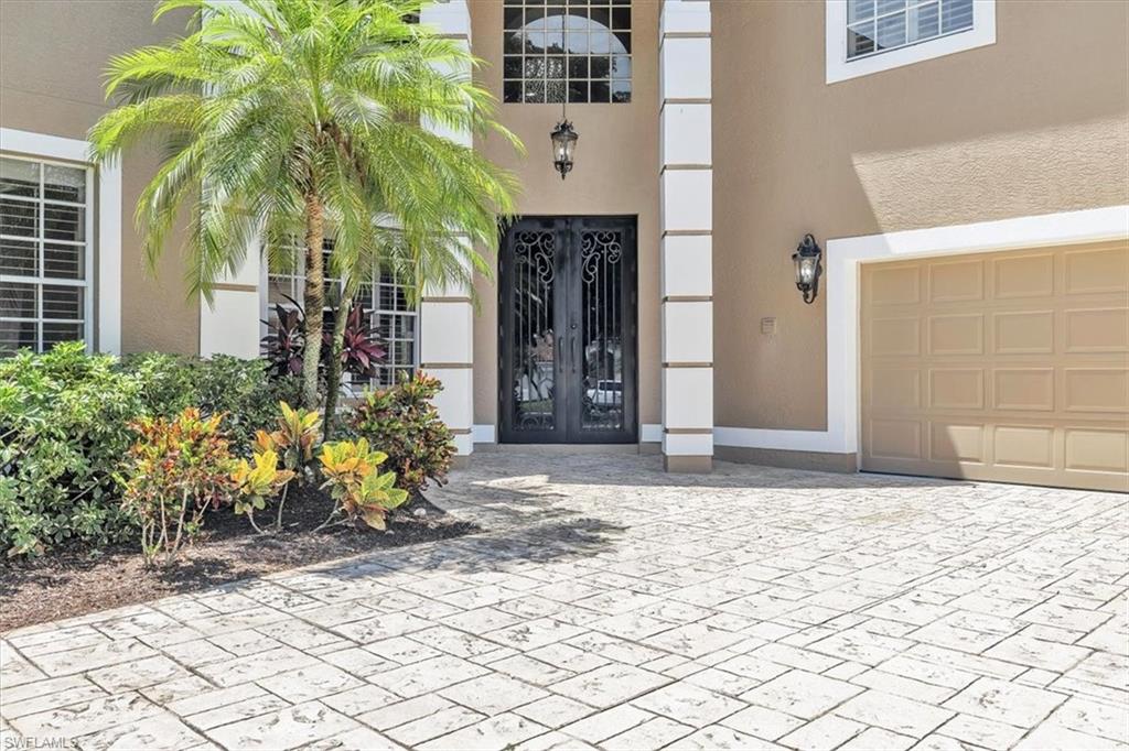 Stucco exterior with decorative columns, ornate double entry doors, an arched transom window, and a paneled garage door