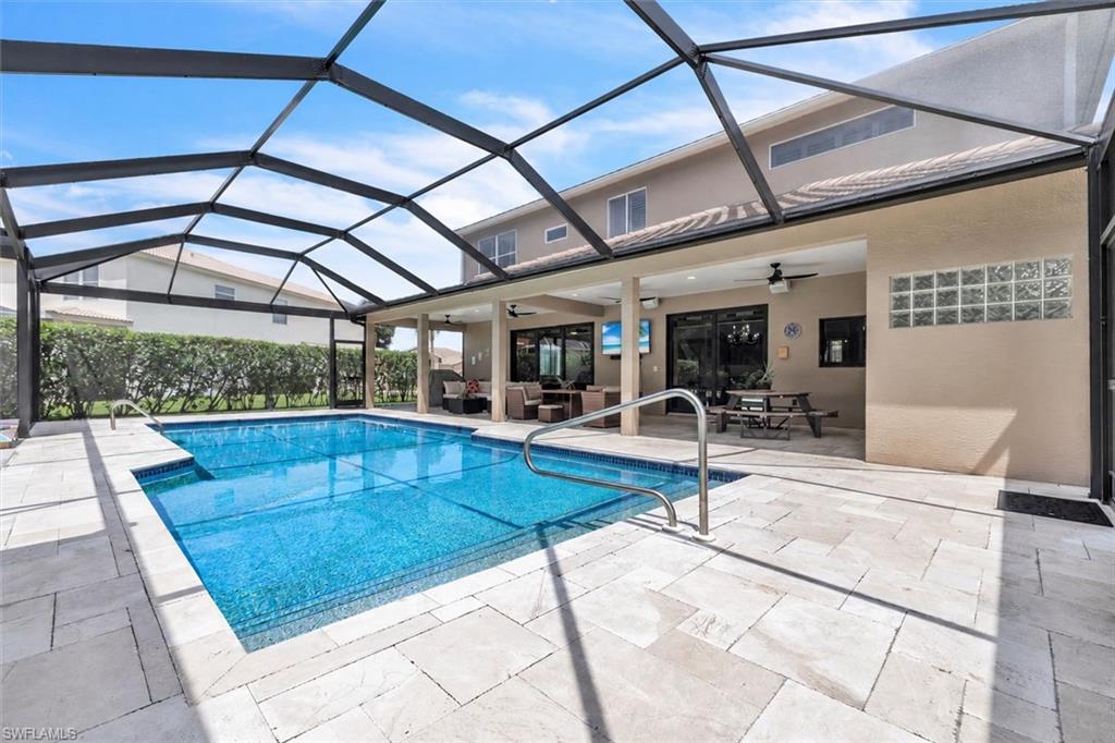 Screened enclosure covering a rectangular pool with a built-in step, surrounded by light-toned paver flooring