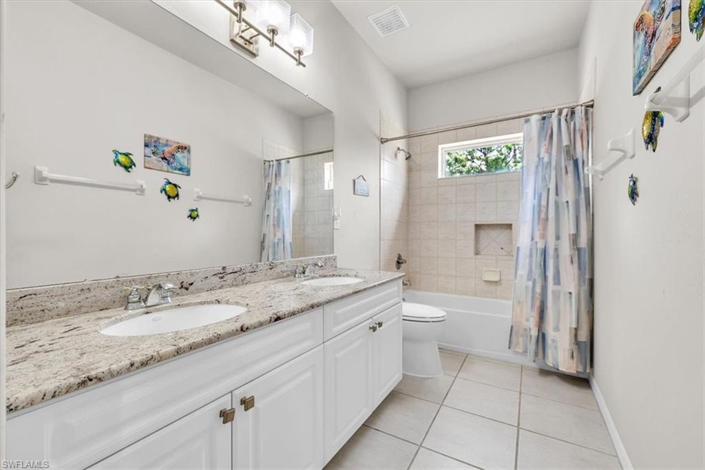 Bathroom featuring a double vanity with stone countertops, dual undermount sinks, and white cabinetry