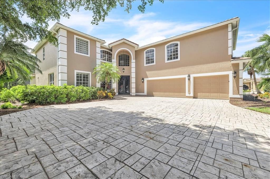 Stucco exterior featuring decorative white banding, an arched entryway, and a stamped concrete driveway