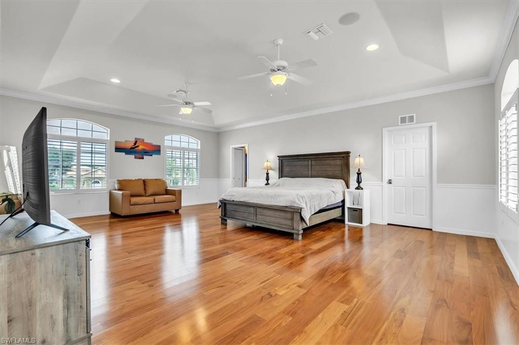 Spacious interior featuring wood-finish flooring, a tray ceiling, and white wall paneling