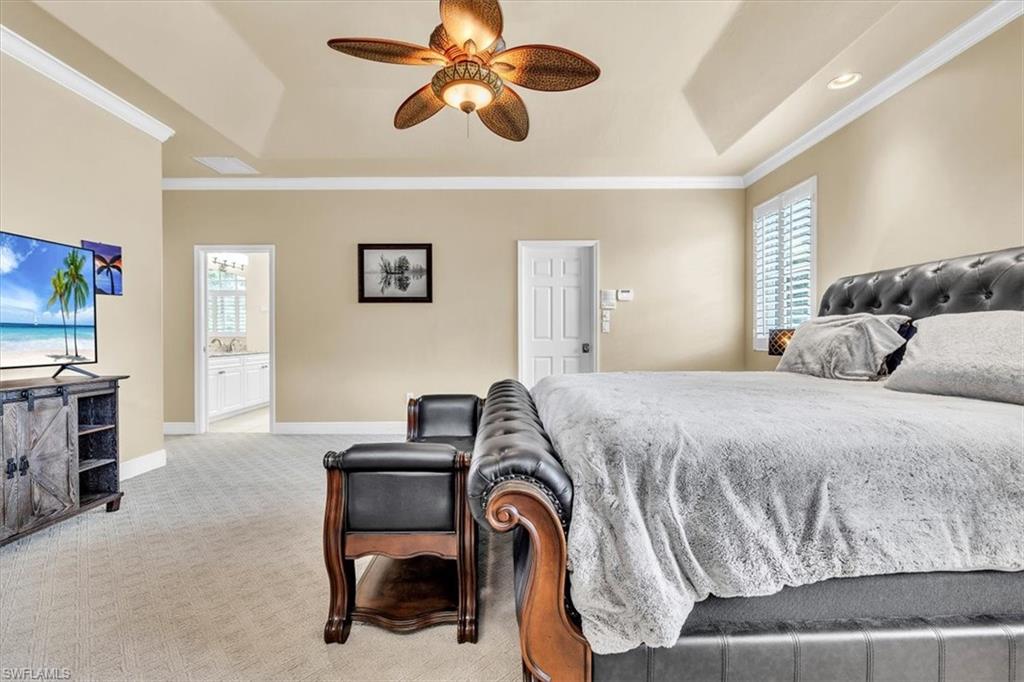 Spacious room featuring a tray ceiling with a ceiling fan, recessed lighting, and crown molding