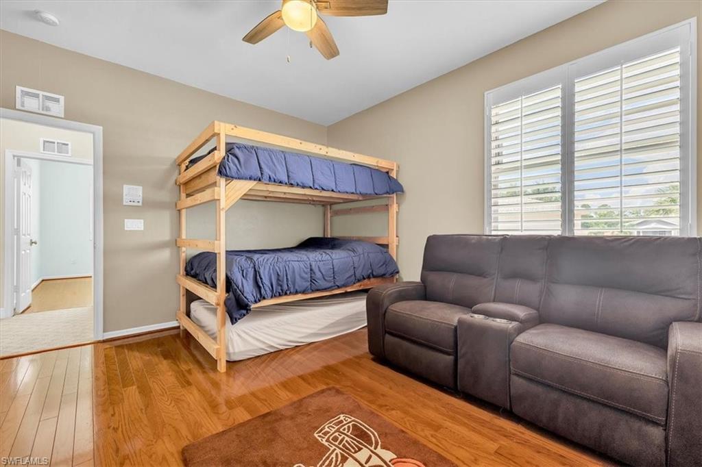 Interior room featuring wood-finish flooring, a ceiling fan with integrated lighting, and multiple windows with plantation shutters