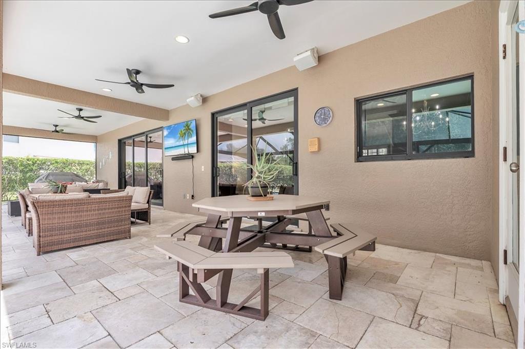 Expansive covered patio featuring large format tile flooring and multiple ceiling fans