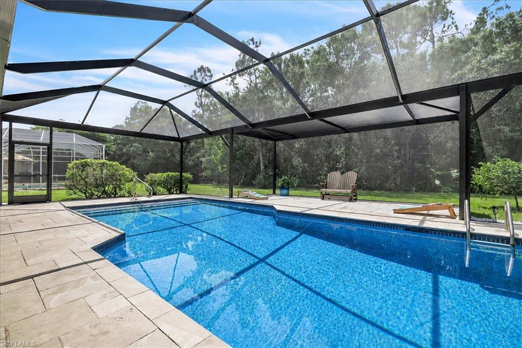 Screened outdoor pool with tiled steps, surrounding paver patio, and dark-framed enclosure