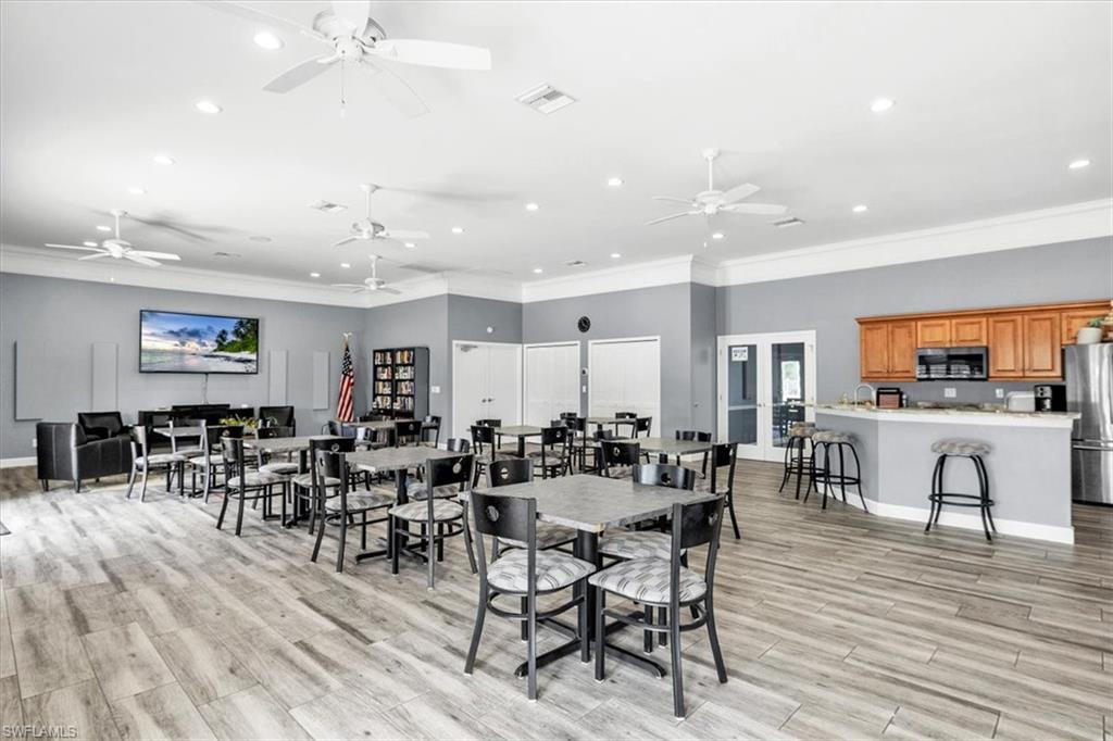 Spacious common area featuring wood-finish flooring, a full kitchen with wood cabinetry and stainless steel appliances, and multiple ceiling fans
