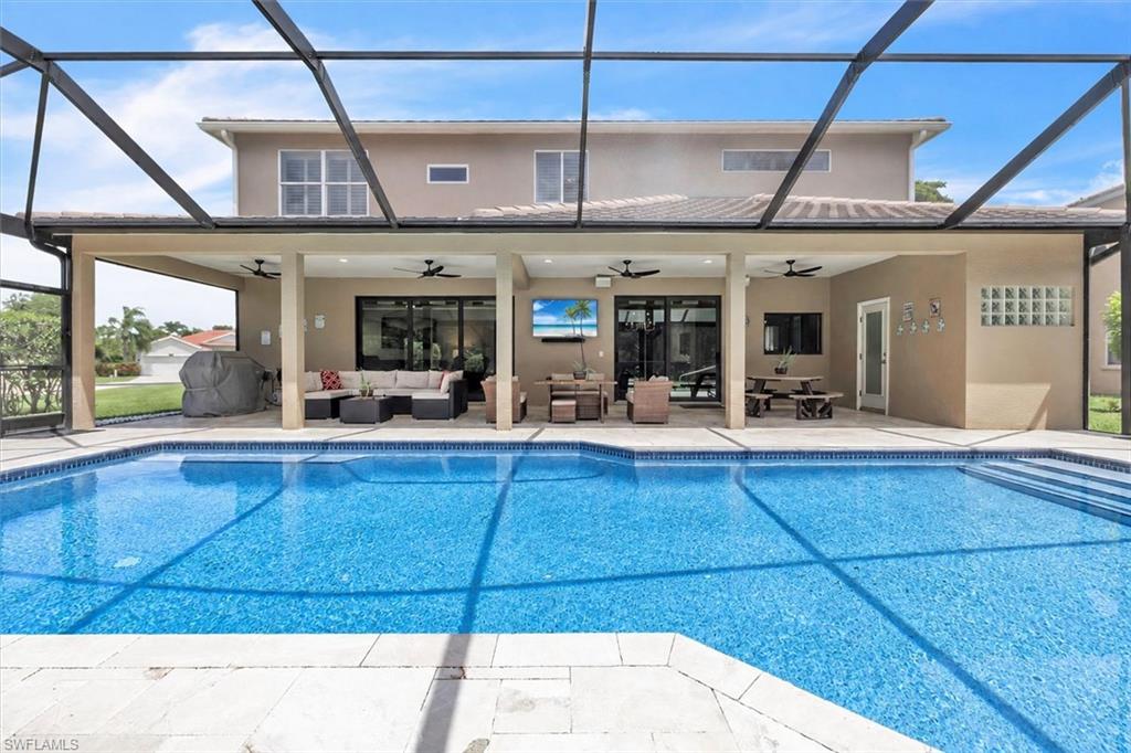 Expansive pool area featuring a screened enclosure, a large swimming pool with integrated steps, an extended covered patio, and multiple large sliding glass doors