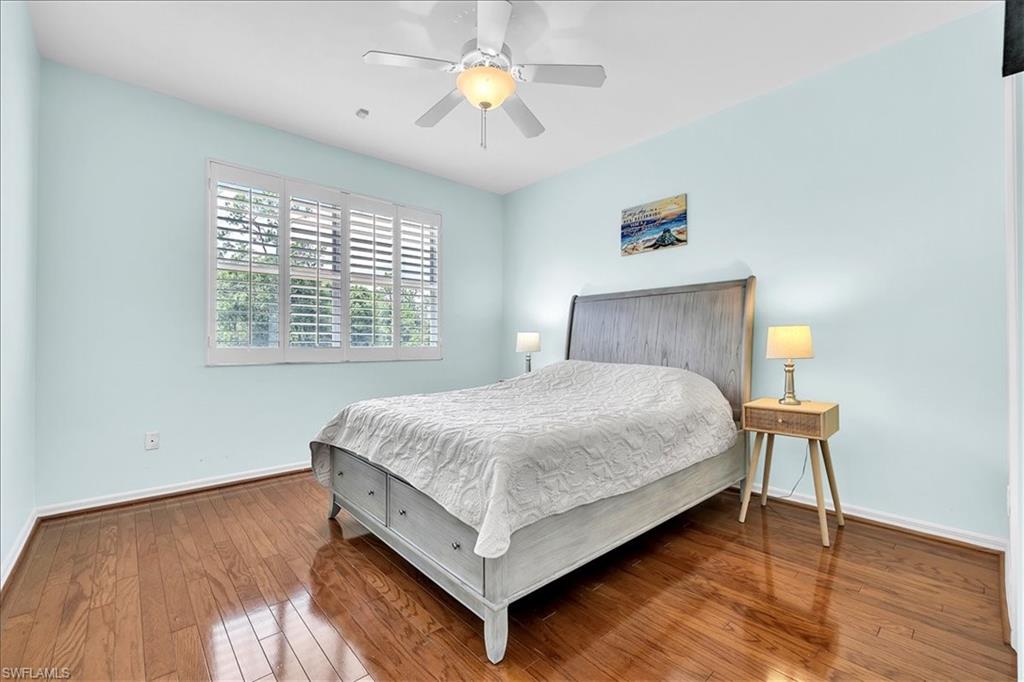 Hardwood flooring throughout featuring white plantation shutters and a ceiling fan with integrated lighting