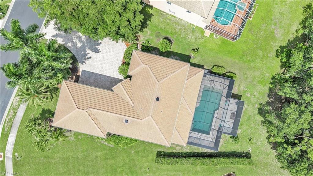 Aerial perspective showcasing a property with a tiled roof and a screened-in swimming pool