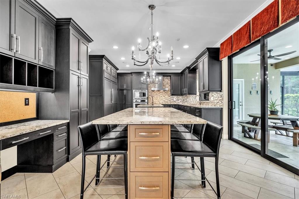 Gourmet kitchen featuring a substantial island with stone countertop, dark wood-finish cabinetry, and stainless steel appliances