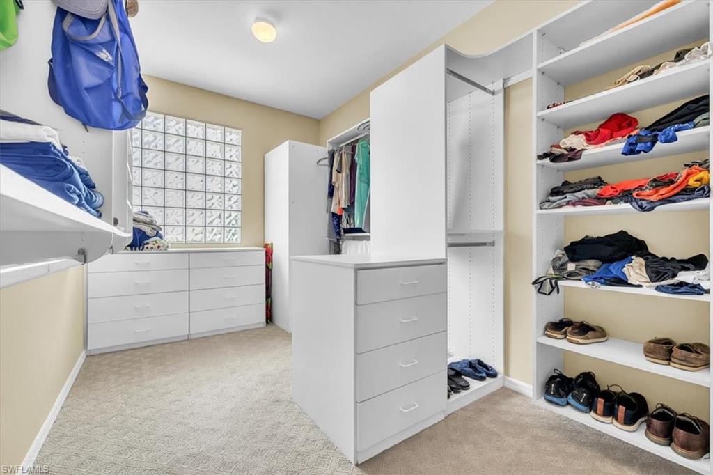 Customized closet system featuring multiple shelving units, built-in drawers, hanging rods, and an integrated central island with additional storage
