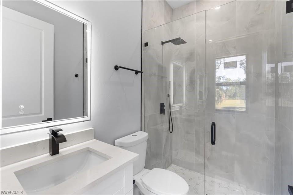 Modern bathroom featuring a frameless glass shower enclosure with matte black fixtures, a rain shower head, and a handheld spray