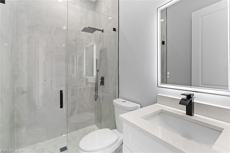 Modern bathroom featuring a glass-enclosed shower with large format tile, a rain shower head, and matte black fixtures