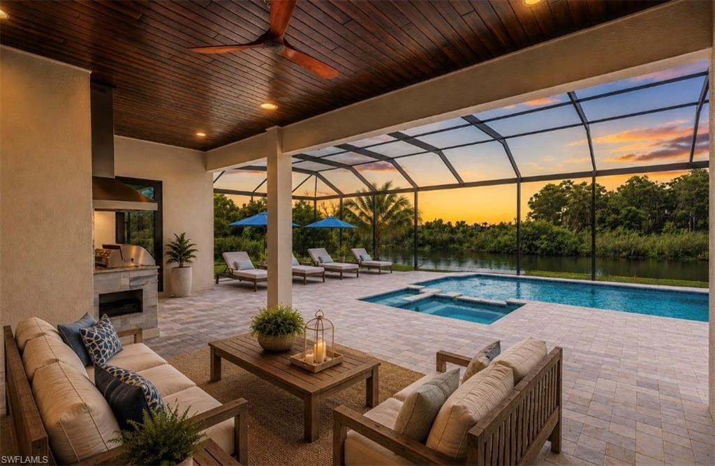 Virtual Staged. Screened lanai featuring a swimming pool, integrated spa, and an outdoor kitchen with built-in grill and stone-clad base