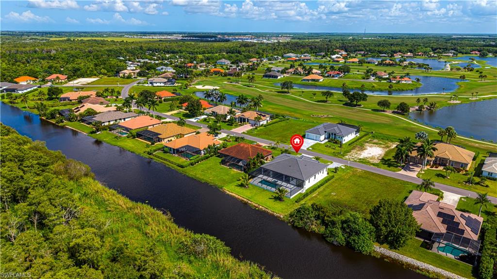 Aerial overview showcasing a property with a screen-enclosed pool, situated alongside a waterway