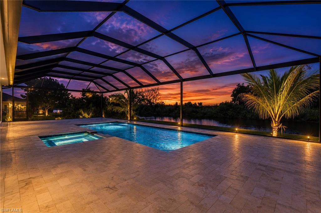 Screened outdoor living area featuring a rectangular pool, integrated spa, and expansive paver patio