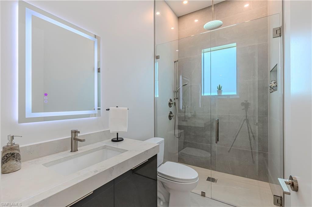 Modern bathroom featuring a glass-enclosed shower with a rainfall showerhead, a built-in shower niche, and a window for natural light