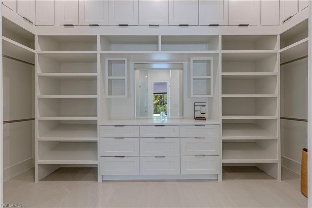 White custom closet system featuring extensive shelving, hanging rods, and built-in drawers