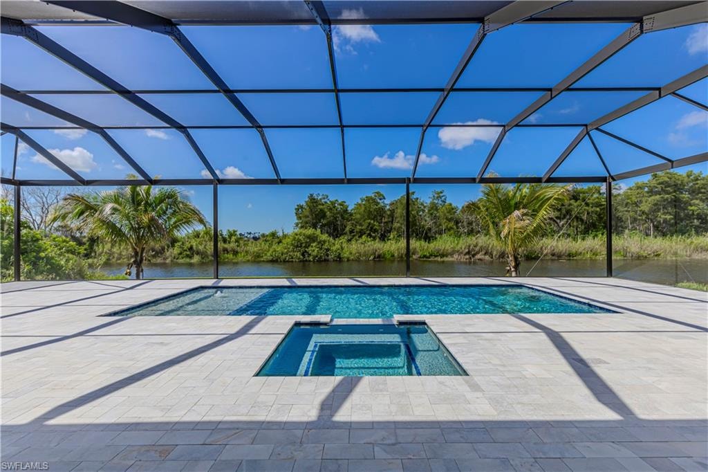 Screened outdoor area featuring a swimming pool, integrated spa, and expansive paver decking