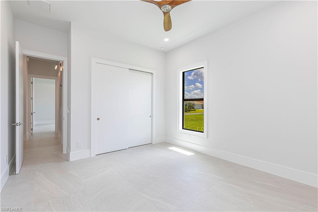 Bedroom featuring light-toned tile flooring, a window with exterior views, and a dual sliding door closet