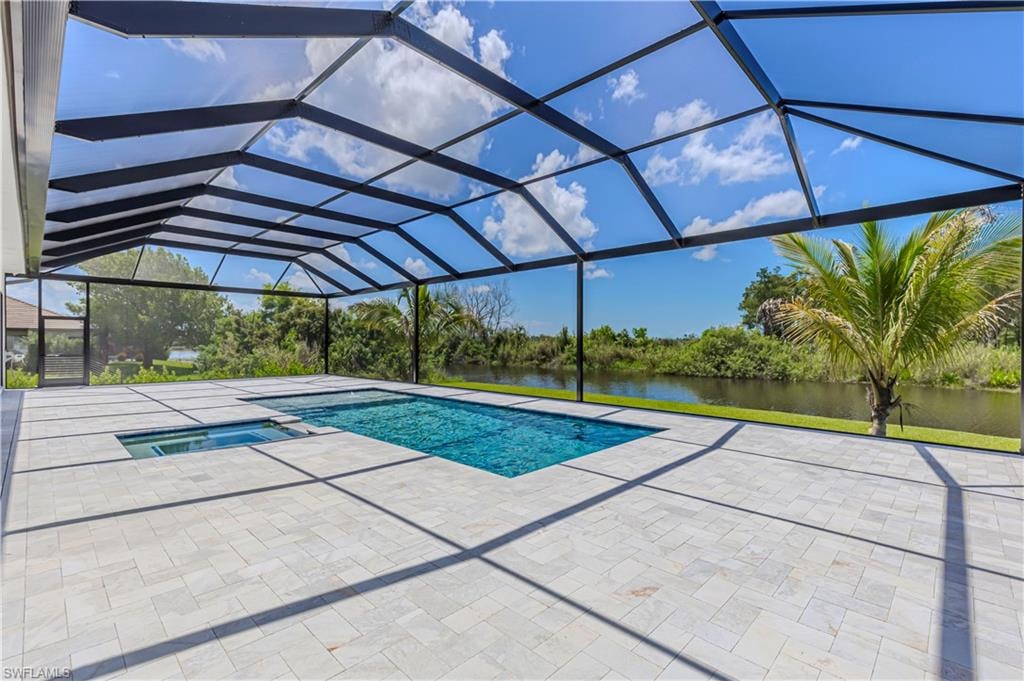 Screened outdoor living space featuring an in-ground swimming pool, integrated hot tub, and expansive paver deck