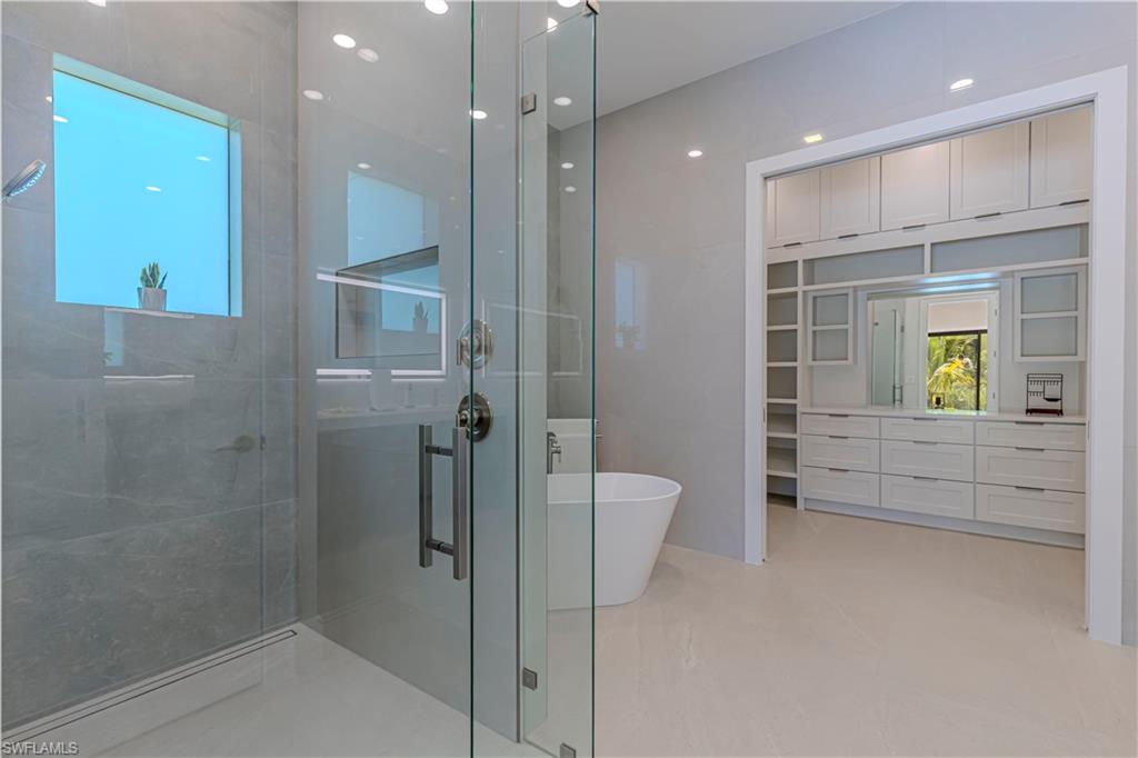 Glass-enclosed shower with gray tiled walls and a horizontal window